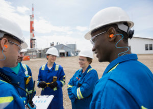 Workers meeting outside gas plant to plan maintenance via a cmms software