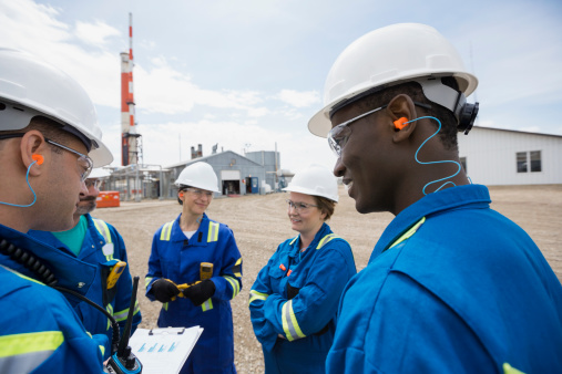 Workers meeting outside gas plant to plan maintenance via a cmms software