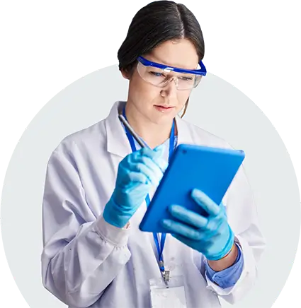 A woman working in life sciences uses eMaint CMMS software on her tablet to create audit trails and track labor and inventory