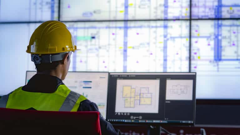 Un ouvrier de maintenance regarde des écrans d'ordinateur