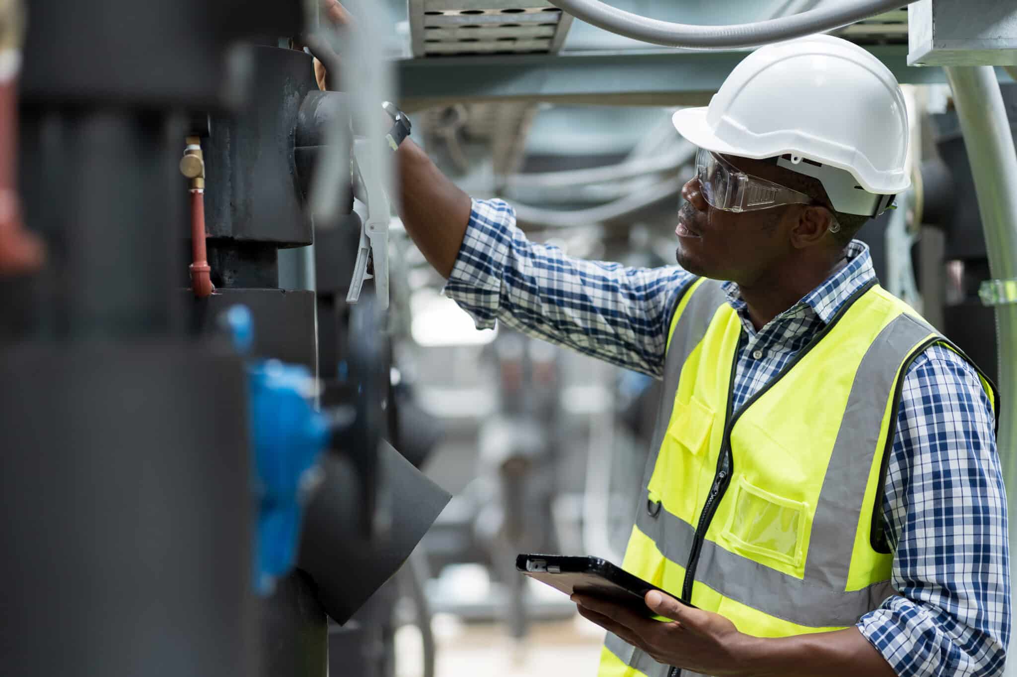 Maintenance worker holding a tablet in a manufacturing facility.