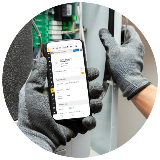 Arbeiter mit grauem Handschuh, der ein mobiles Gerät hält und den Bildschirm der eMaint CMMS EAM-App betrachtet