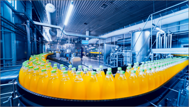Bottles being filled with orange colored drink in bottling plant